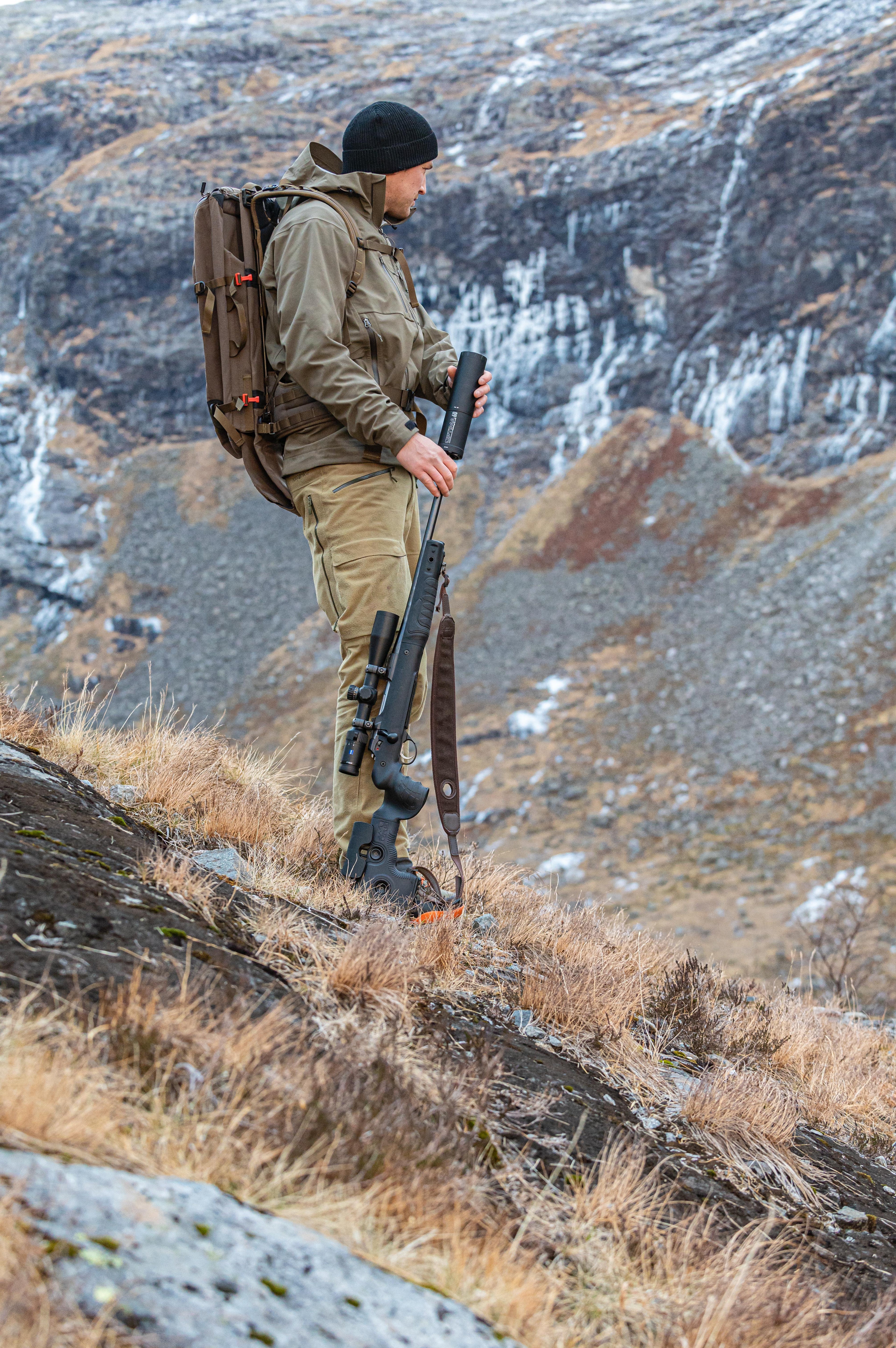 Mann mit Gewehr und Rucksack in der Natur.